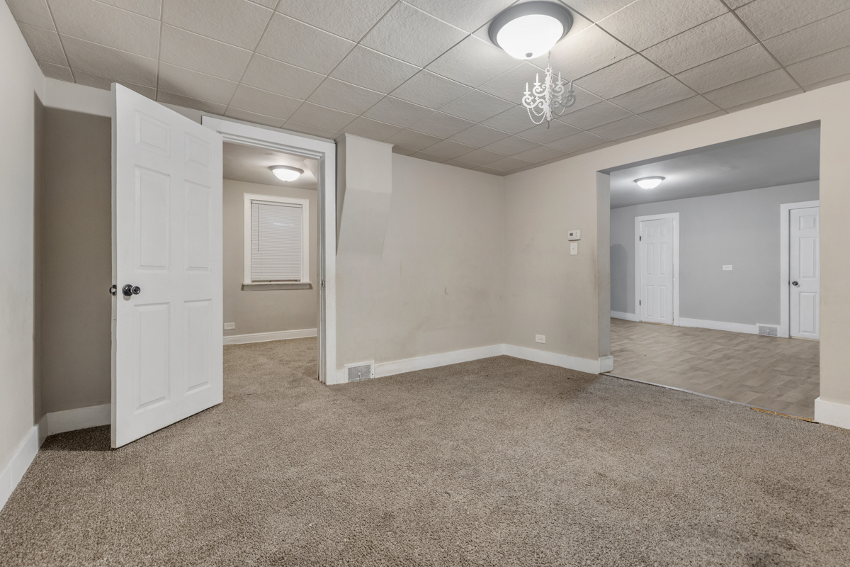 631 East 142nd Street Dolton, IL 60419 - Photo 9 of 29 an empty room with a chandelier fan and windows