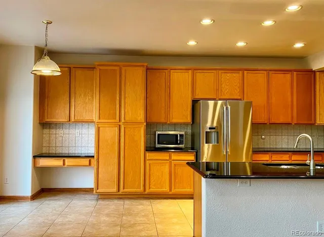 a kitchen with stainless steel appliances granite countertop a refrigerator a stove and a sink with cabinets