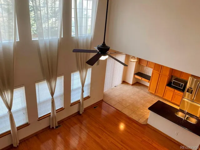 an empty room with wooden floor fan and windows