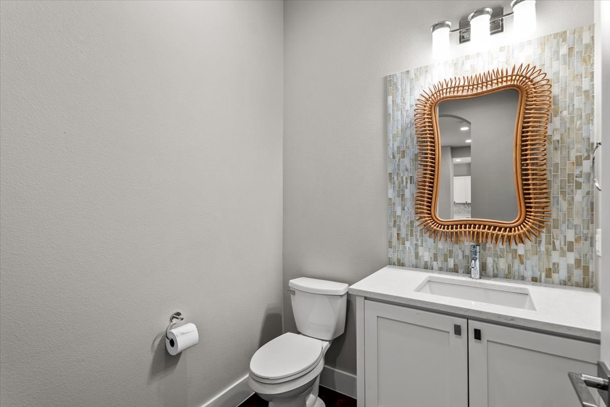 913 Stobaugh Street, Unit B Austin, TX 78757 - Photo 22 of 40 A well-appointed powder room features a vanity with sleek counters and a decorative mirror, illuminated by vanity lighting.