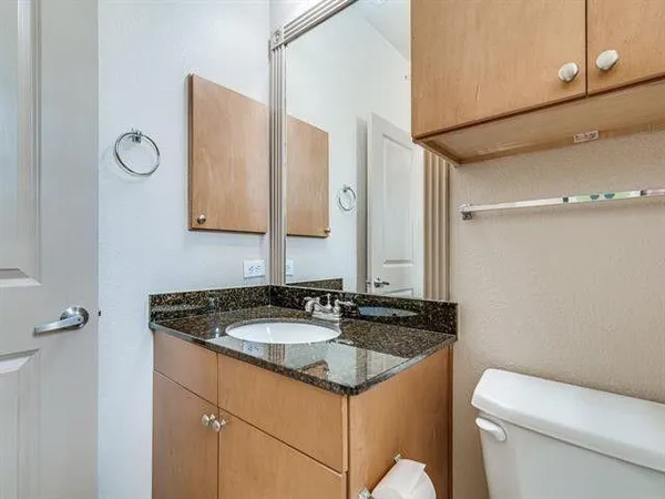 a bathroom with a granite countertop sink and a toilet