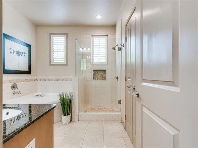 a bathroom with a granite countertop sink a mirror and a bathtub