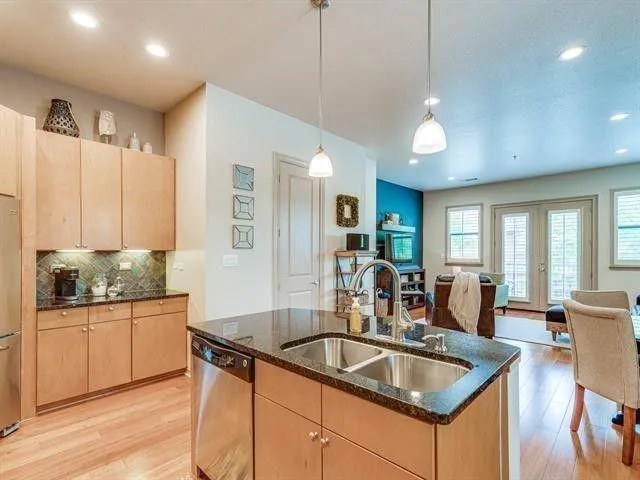 a kitchen with stainless steel appliances granite countertop a sink a stove and wooden floors