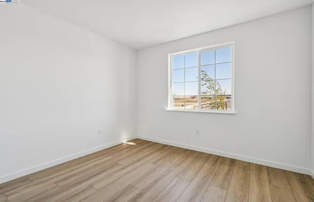 an empty room with a window and wooden floor