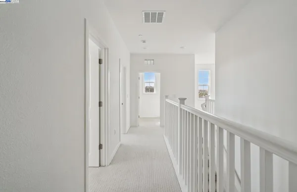 a view of a hallway with wooden floor and a bathroom