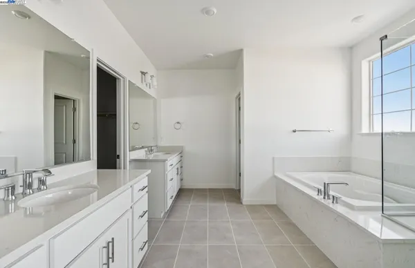 a spacious bathroom with a double vanity sink a mirror a bathtub and shower