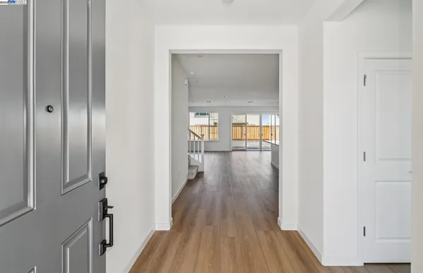 a view of a hallway with wooden floor and a living room
