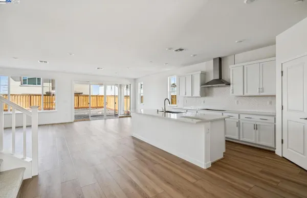a kitchen with stainless steel appliances granite countertop a white cabinets a sink dishwasher and a stove with wooden floor