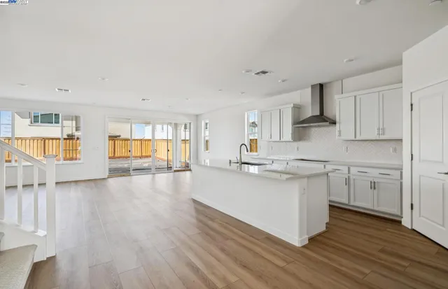 a kitchen with stainless steel appliances granite countertop a white cabinets a sink dishwasher and a stove with wooden floor