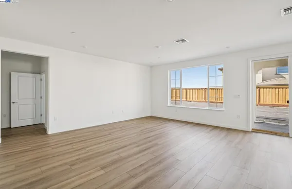 a view of an empty room with wooden floor and windows