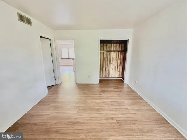 a view of an empty room with wooden floor and closet