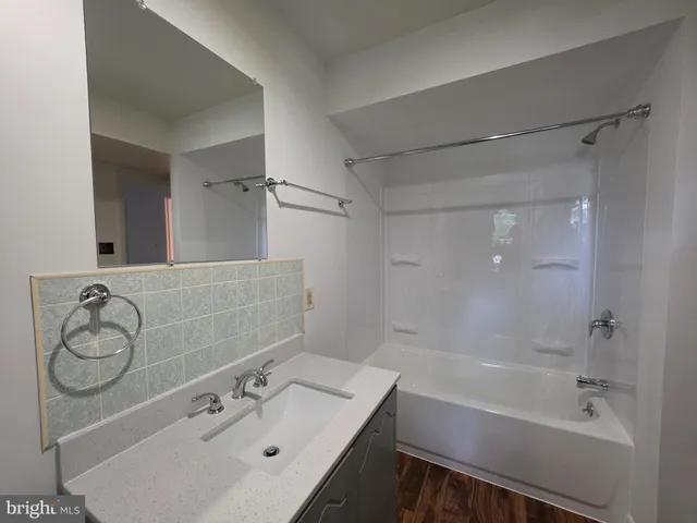 a bathroom with a bathtub shower sink vanity and a toilet