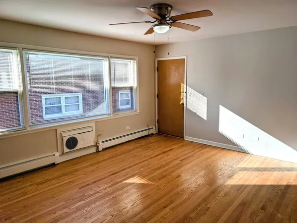 a view of an empty room with a window and wooden floor