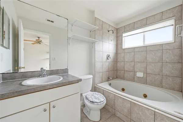 a bathroom with a granite countertop sink a toilet and bathtub
