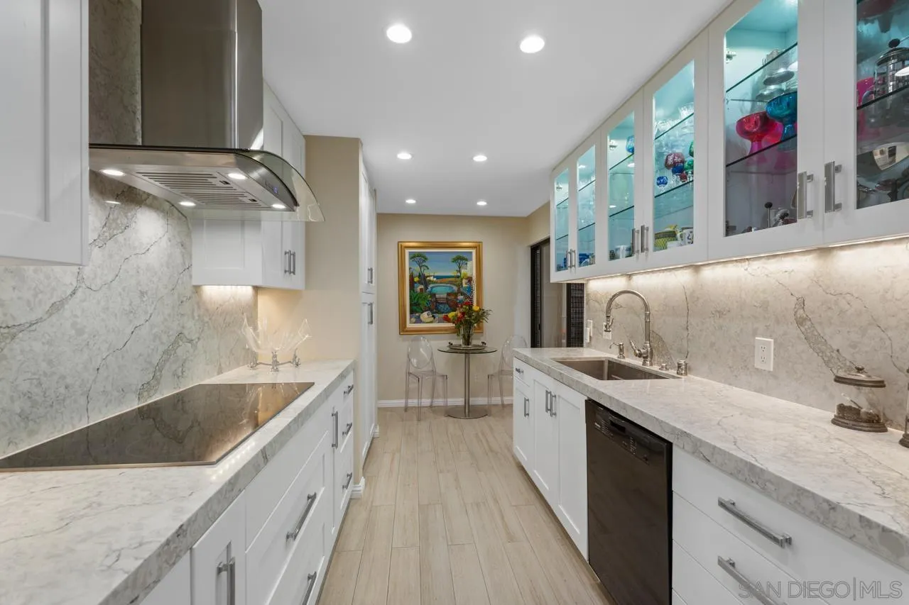 100 Coast Boulevard, Unit 302 La Jolla, CA 92037 - Photo 8 of 21 a large kitchen with stainless steel appliances kitchen island granite countertop a sink and cabinets