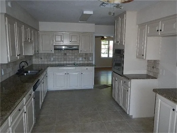 a kitchen with kitchen island granite countertop a sink stove and cabinets