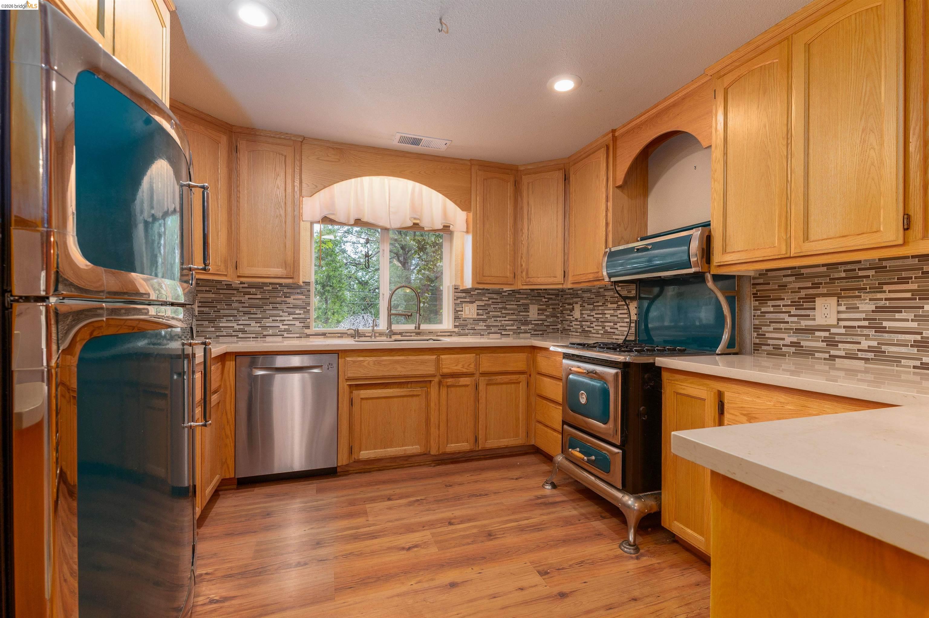 22401 Ridge Road Twain Harte, CA 95383 - Photo 8 of 56 Kitchen with wood-finish flooring, light wood cabinetry, and a mosaic tile backsplash