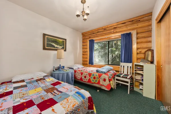 a bedroom with two beds and a dresser next to a window