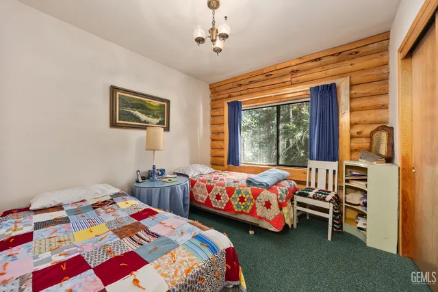 a bedroom with two beds and a dresser next to a window