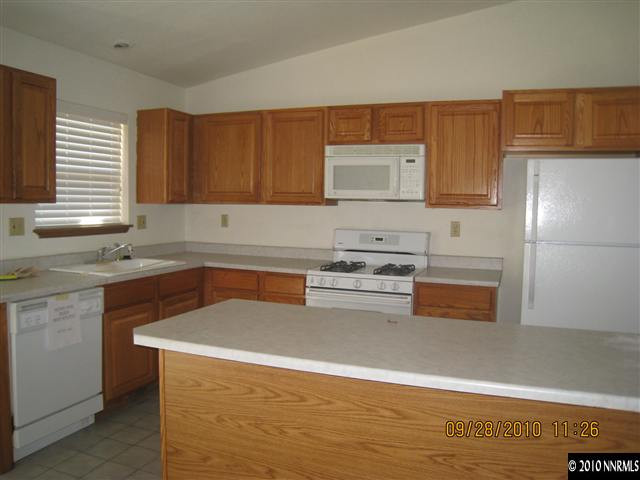 1690 Laiolo Drive Reno, NV 89502 - Photo 4 of 6 a kitchen with stainless steel appliances granite countertop a sink dishwasher stove and microwave with wooden cabinets