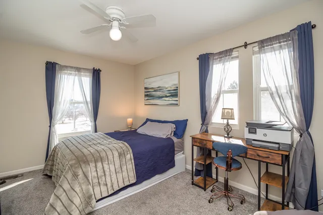 a bedroom with a bed work place and a large window