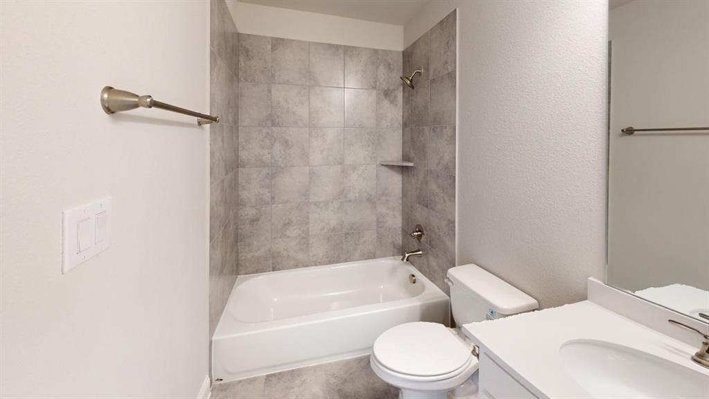 8407 Cornerstone Drive Rowlett, TX 75088 - Photo 6 of 25 Bathroom featuring a white bathtub with a tiled shower surround, a built-in shower niche, a white toilet, and a vanity with an integrated sink and brushed nickel faucet