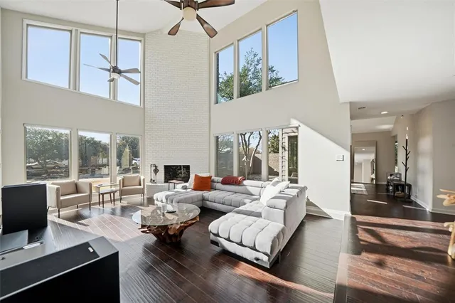a living room with furniture large window and wooden floor