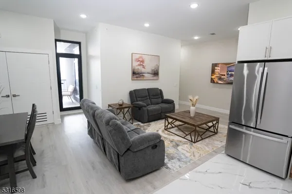 a living room with furniture and a refrigerator