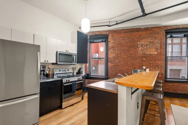 a kitchen with stainless steel appliances kitchen island granite countertop a refrigerator a stove top oven a sink dishwasher and a refrigerator