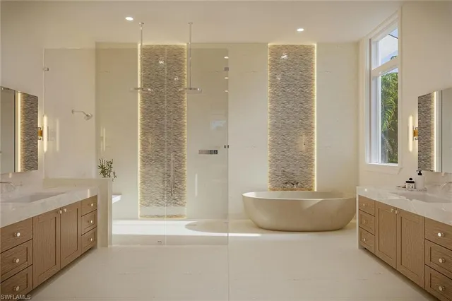 a bathroom with a tub sink double vanity granite tub shower and mirror