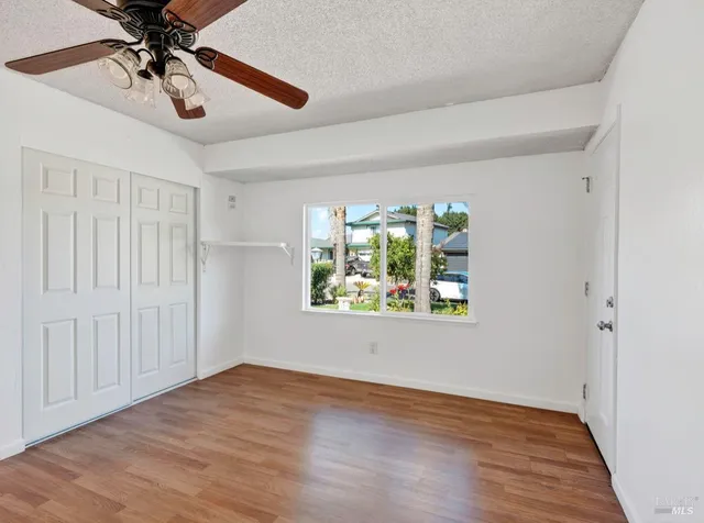 a view of an empty room with a window and kitchen view