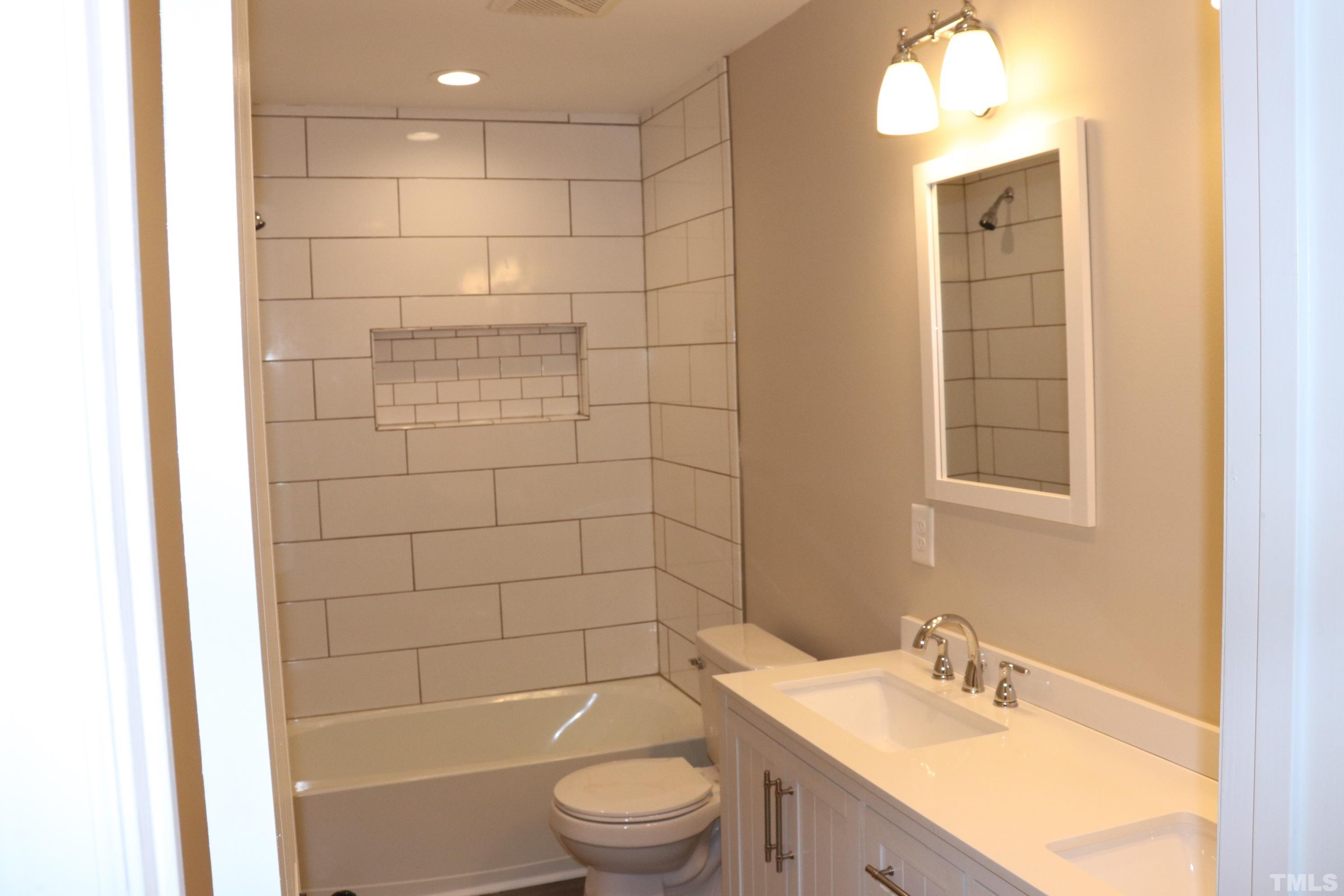 1108 Wyldewood Road Durham, NC 27704 - Photo 19 of 35 a bathroom with a bathtub shower sink vanity and toilet