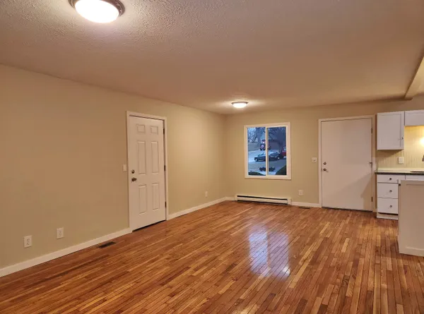 a view of an empty room with wooden floor and a window