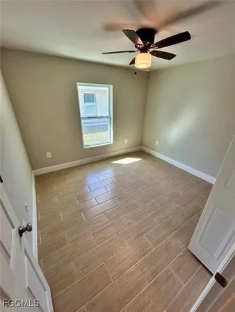 an empty room with windows and ceiling fan