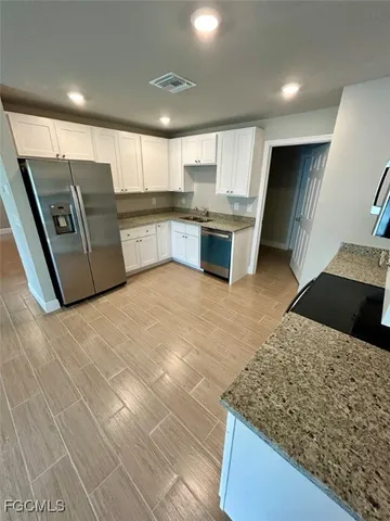 a large kitchen with stainless steel appliances kitchen island granite countertop a sink and cabinets