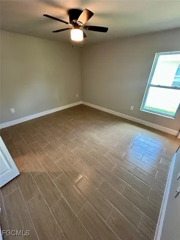 an empty room with a window and ceiling fan