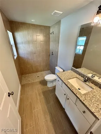 a bathroom with a granite countertop sink toilet and shower