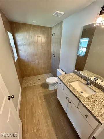 a bathroom with a granite countertop sink toilet and shower