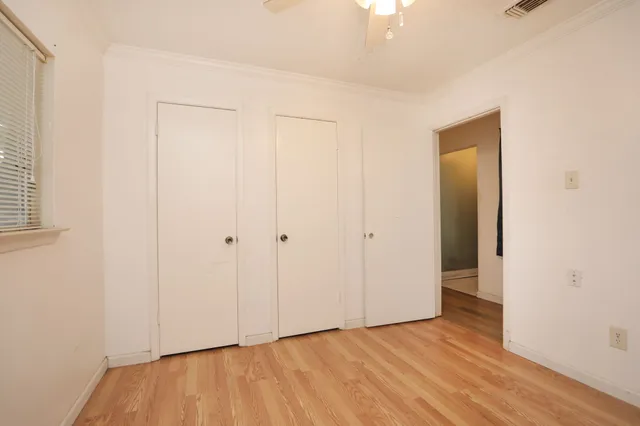 a view of an empty room with wooden floor and closet