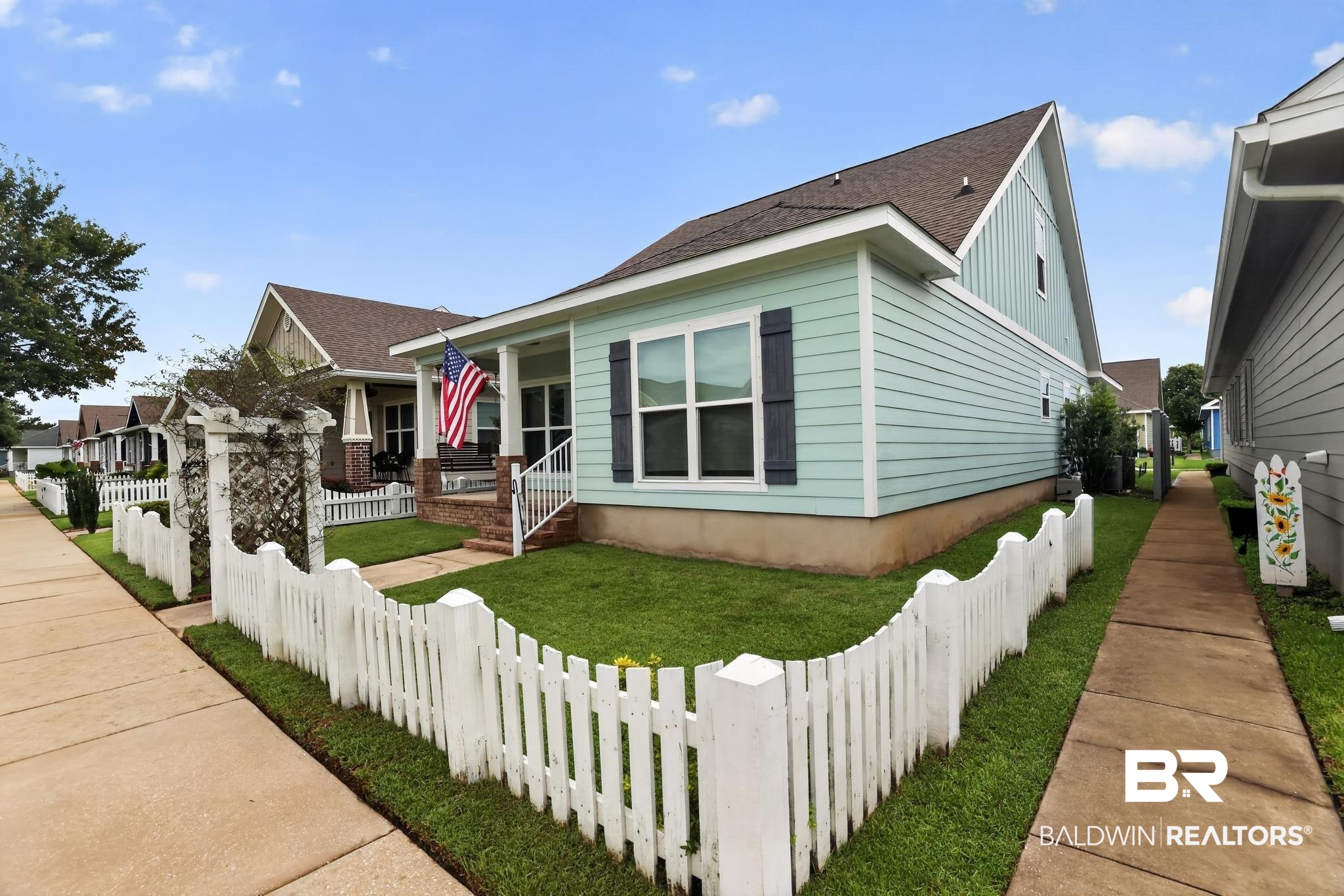1210 Primrose Lane Foley, AL 36535 - Photo 2 of 33 Light blue siding exterior with dark shutters, featuring a covered front porch, white railing, and brick stairs