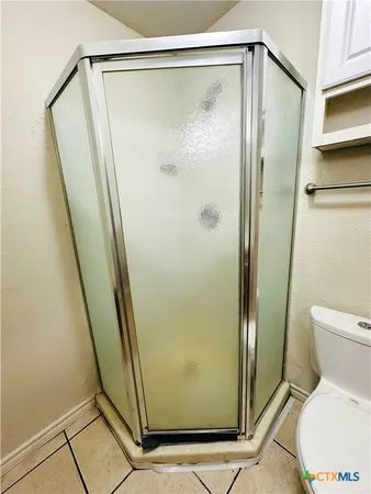 a bathroom with a glass door shower and a toilet