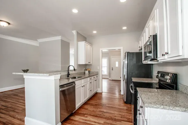 a large kitchen with stainless steel appliances granite countertop a stove refrigerator and a sink