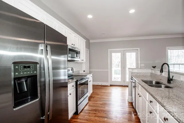 a kitchen with stainless steel appliances granite countertop a refrigerator a sink and a stove