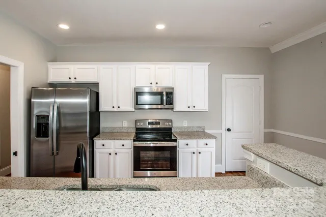 a kitchen with stainless steel appliances kitchen island granite countertop a refrigerator oven a sink and dishwasher
