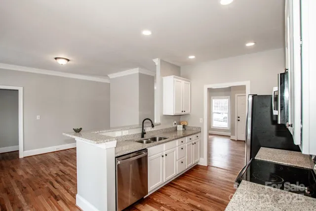 a large white kitchen with a sink and dishwasher a stove with wooden floor