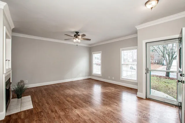 a view of an empty room with wooden floor and a window