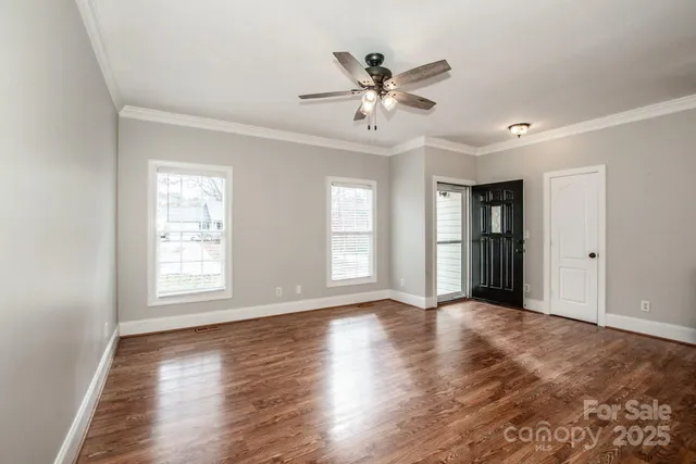 a view of an empty room with wooden floor and a window