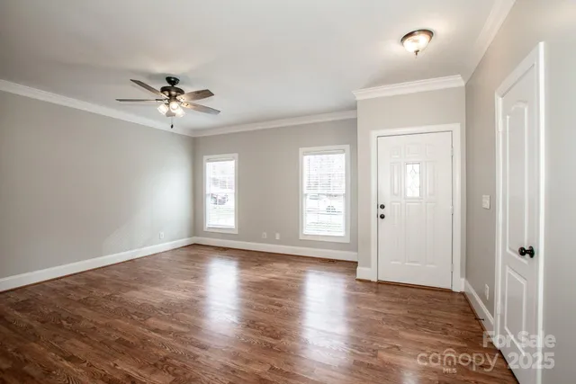 a view of empty room with wooden floor and fan