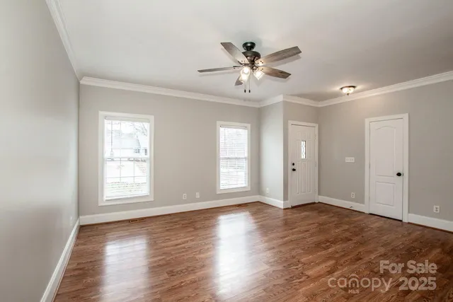 a view of an empty room with wooden floor and a window