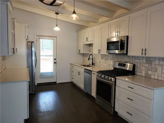 a kitchen with granite countertop a refrigerator a stove a microwave and wooden floor